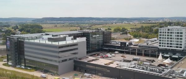 Moderne kantoorcomplex met groen landschap op achtergrond.