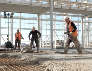 Bouwvakkers storten beton in constructie gebied.