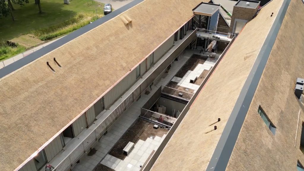 Luchtfoto van gebouw met rieten dak en binnenplaats.