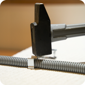 Hamer slaat spijker in kabelklem.