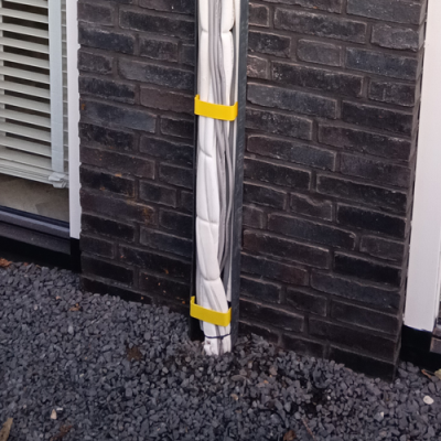 Isolatiebuizen bevestigd op zwarte bakstenen muur.