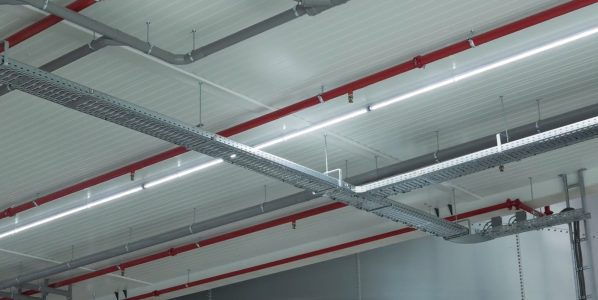 Plafond met leidingen en kabelgoten in fabriekshal.