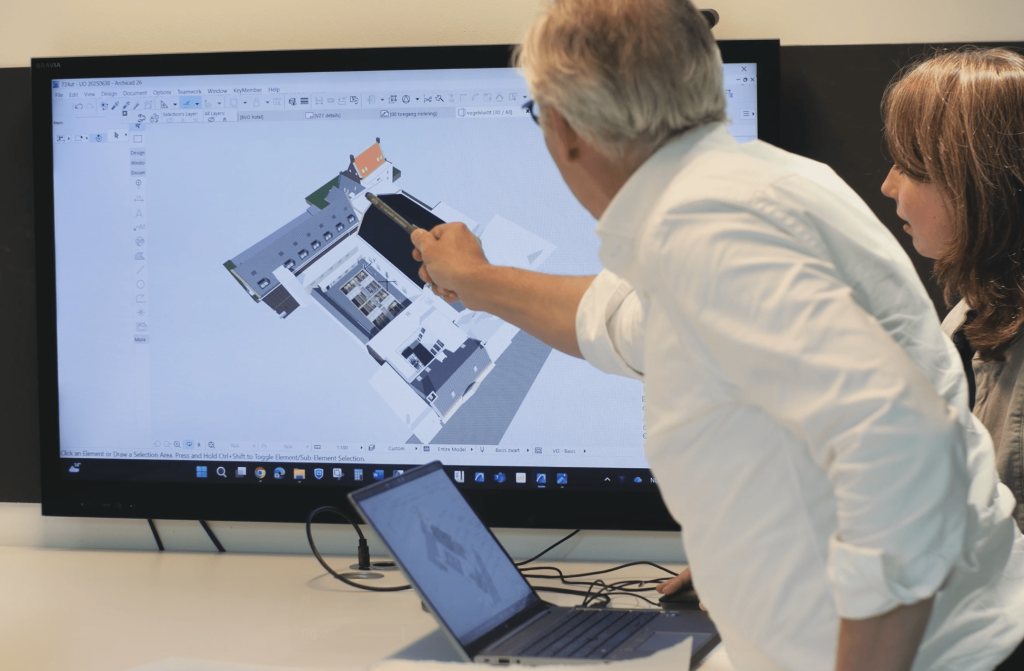 Architecten bespreken bouwmodel op computerscherm.