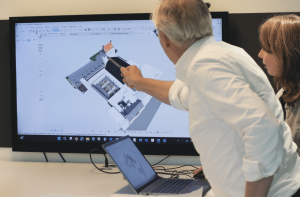 Architecten bespreken bouwmodel op computerscherm.