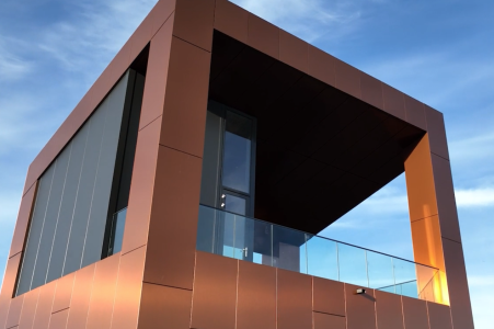 Moderne hoekige gebouw met glas en metaal, blauwe lucht.