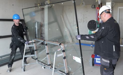 Bouwvakkers tillen groot raam in gebouw