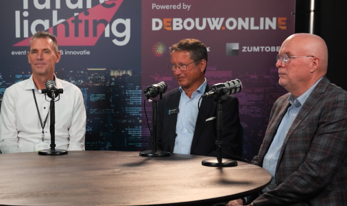Drie mannen in gesprek tijdens conferentie over verlichting.