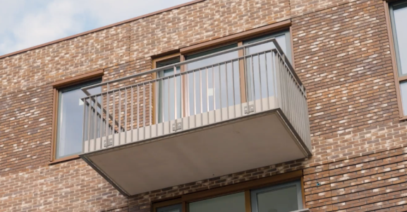 Bakstenen gebouw met metalen balkon.