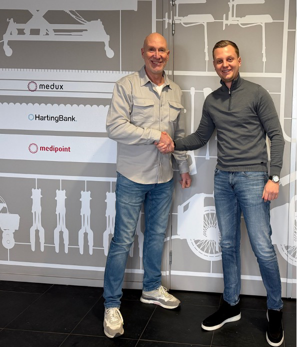 Twee mannen schudden handen voor bedrijfsmuur.