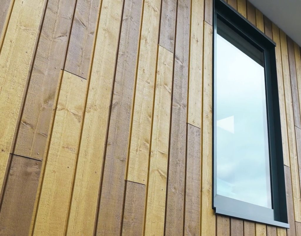 Houten gevel met raam en blauwe lucht.