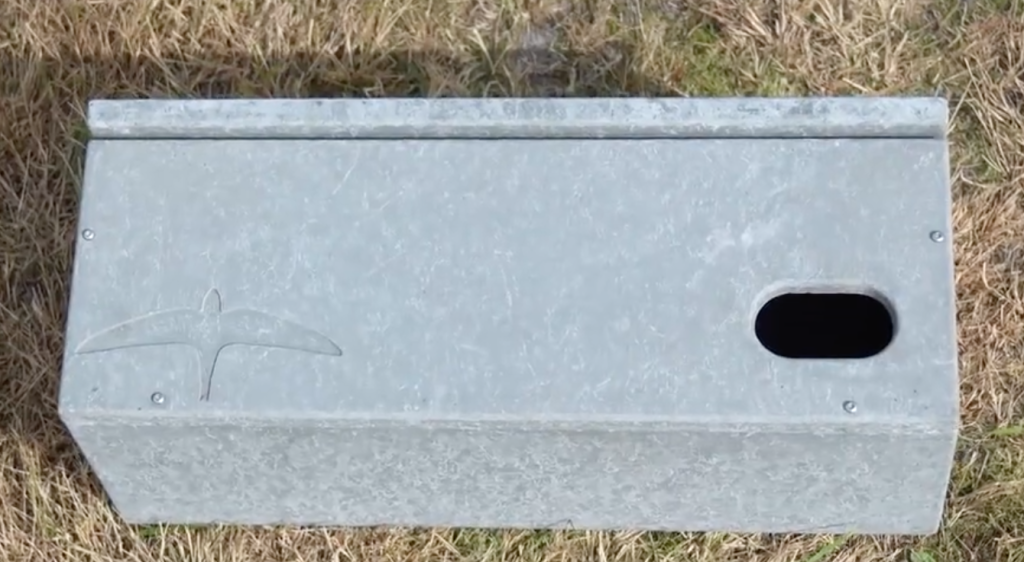 Metalen nestkast met ovale opening op gras