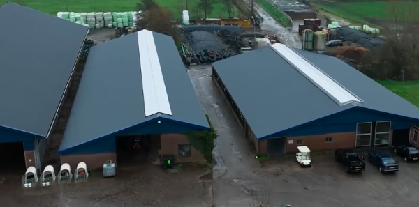 Luchtfoto van boerenschuur met parkeerplaats en veld.