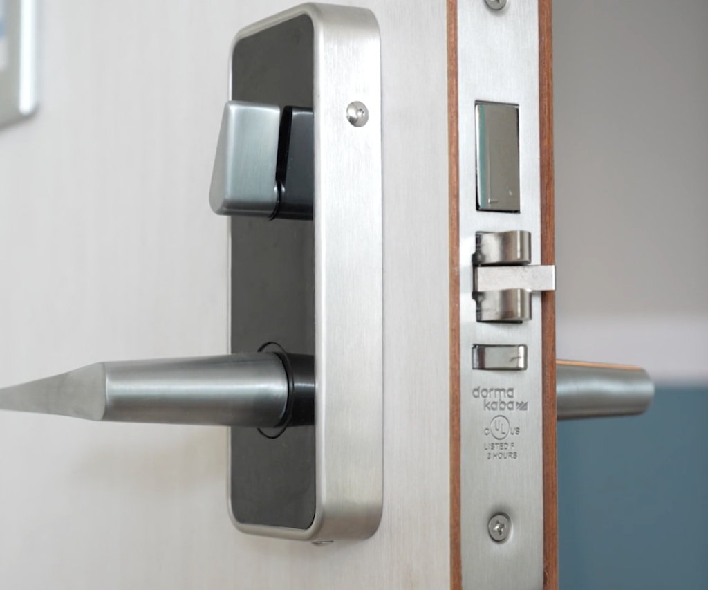 Zilveren deurklink en modern slot op houten deur.