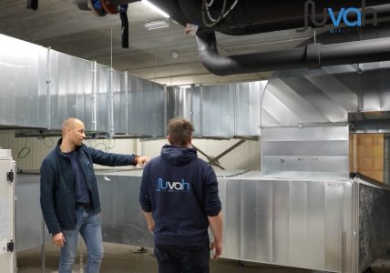 Twee mannen inspecteren luchtventilatiesysteem in gebouw.
