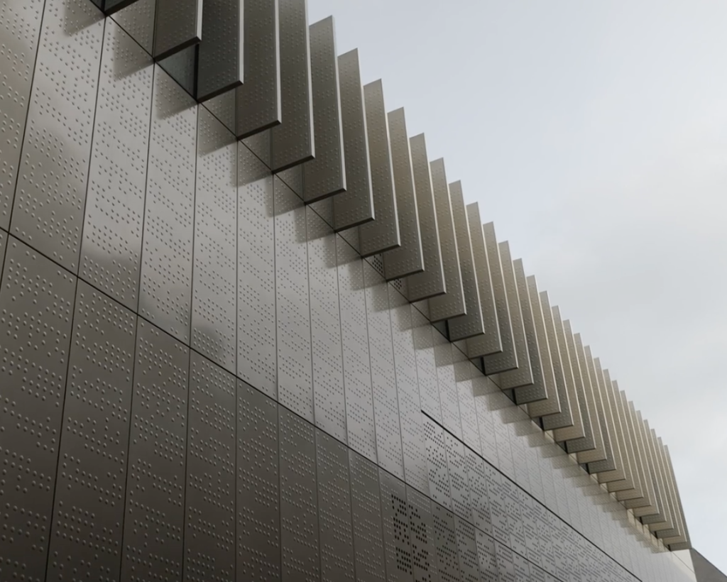 Grijs, modern gebouw met gegolfde gevel details.