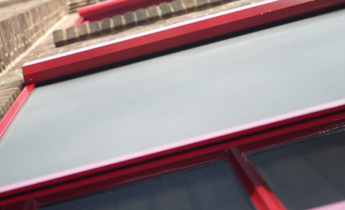 Close-up van een rood kozijn met zonwering