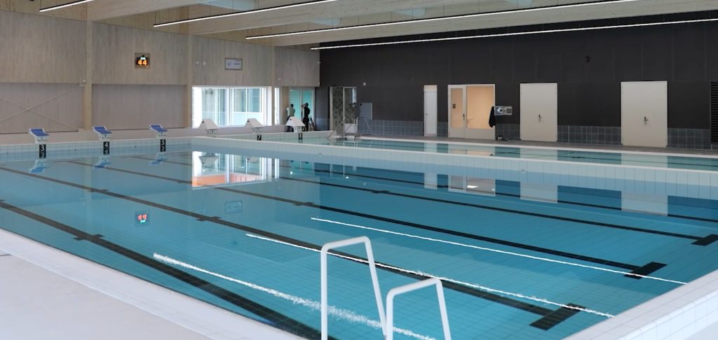 Leeg binnenzwembad met startblokken en water.