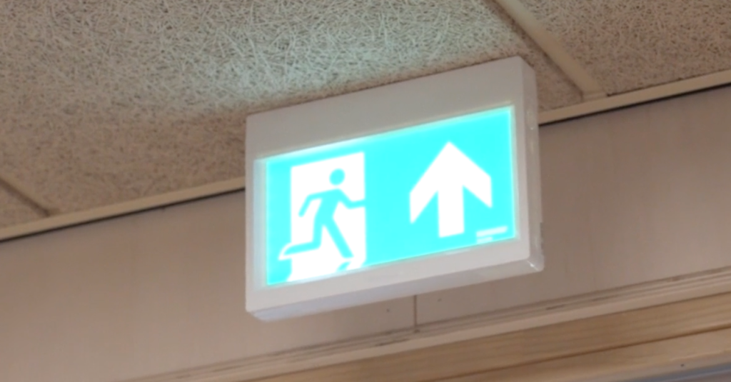 Verlichte nooduitgangsbord met pijl omhoog.